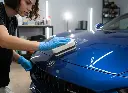 Professional detailer applying ceramic coating on a blue car hood using V TEVO applicator block.